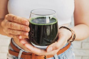 Woman holding Glass of Green Juice - Spirulina Health Benefits